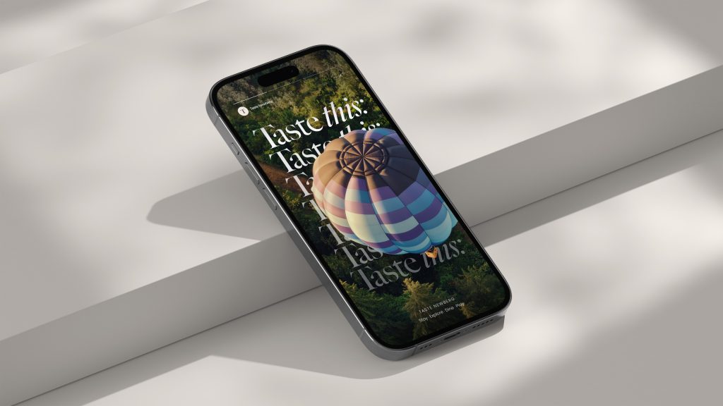 A smartphone displaying a ‘Taste Newberg’ digital campaign with elegant typography and a hot air balloon image.