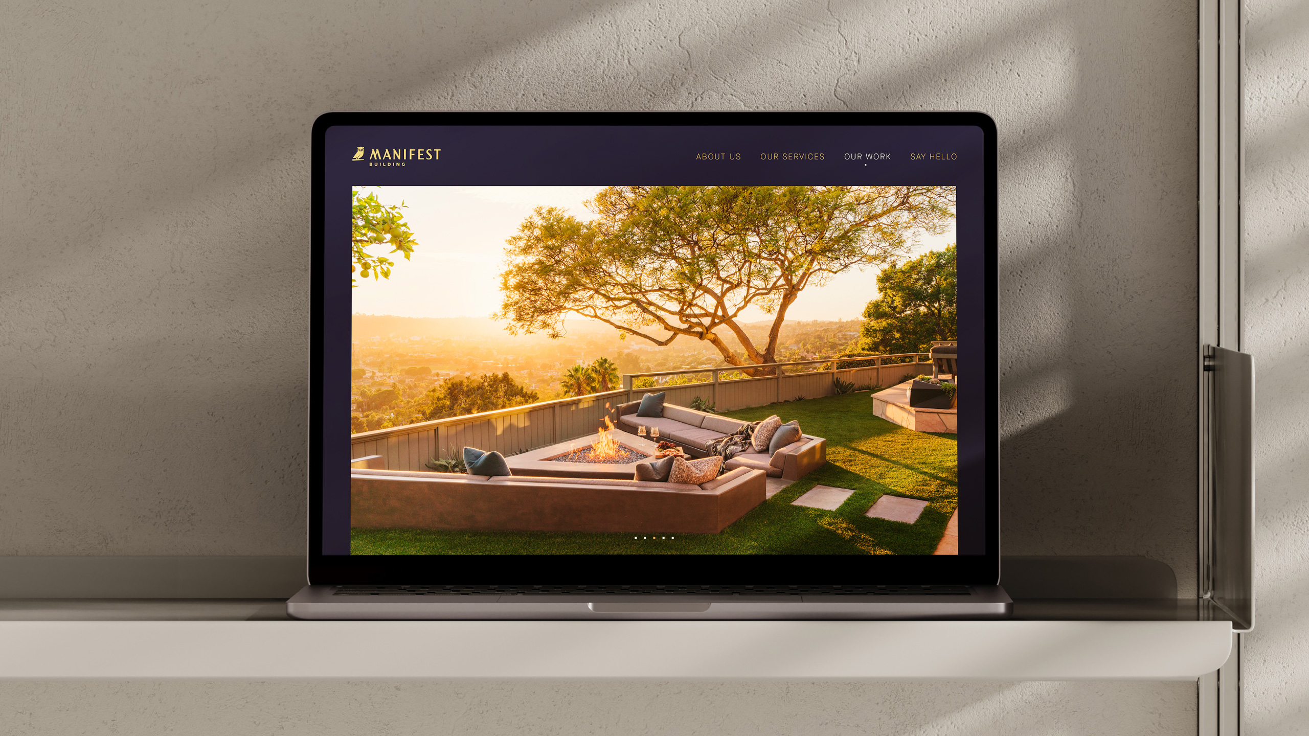 Laptop displaying the homepage of Manifest Building’s website, featuring a luxury outdoor living space with fire pit, custom seating, and panoramic views in Montecito, California. The site reflects the firm’s expertise in high-end landscape design and construction across Santa Barbara.